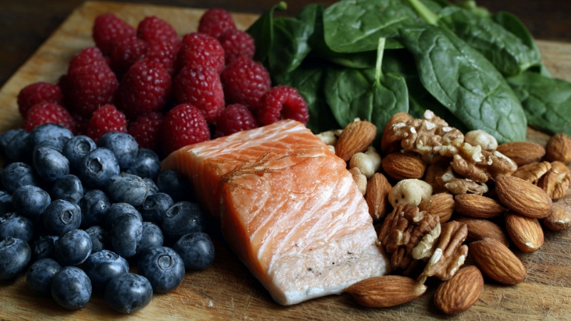 Borovnice, maline, losos, bademi, orasi i spanać na drvenoj dasci